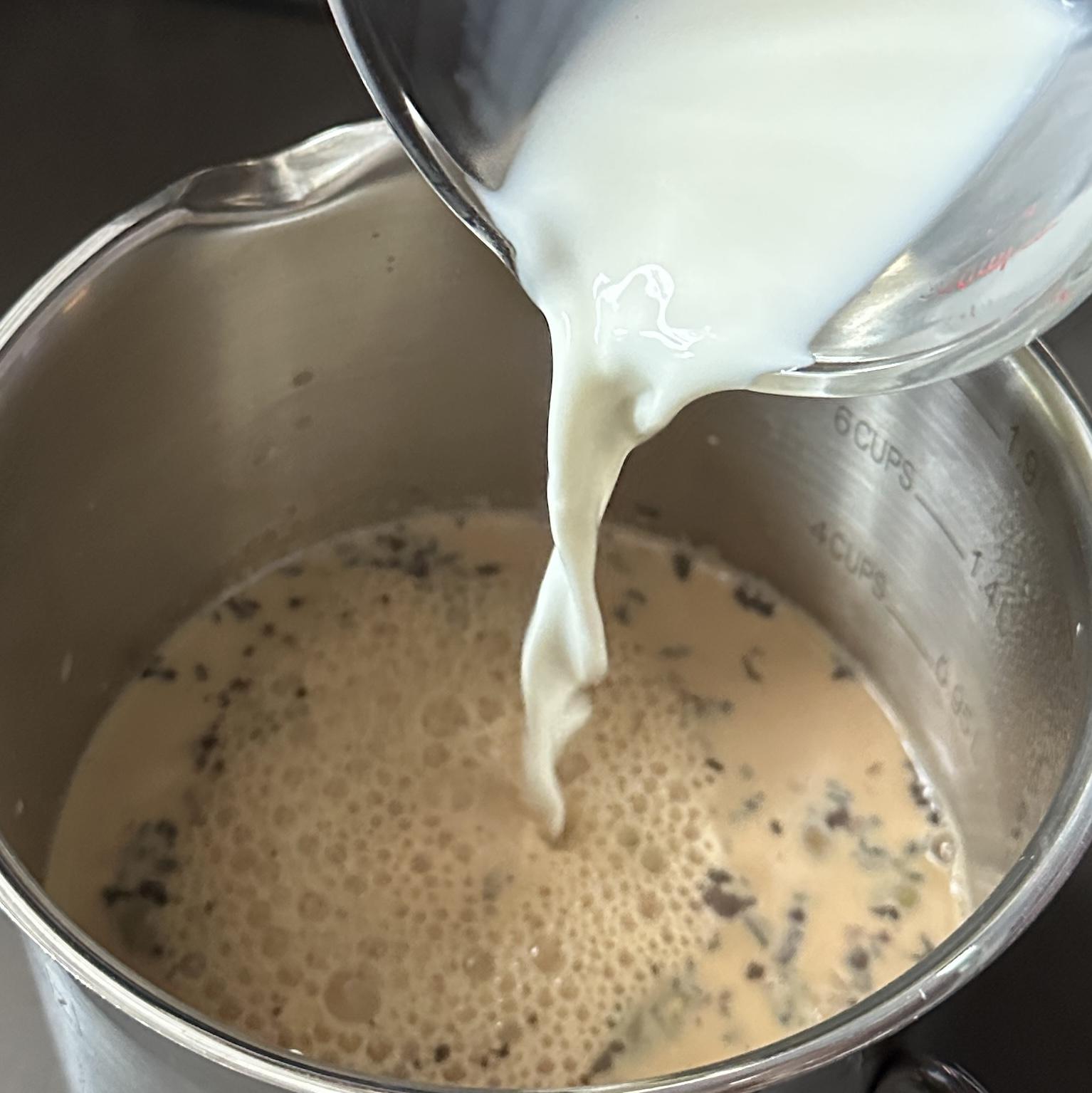 Whole milk being poured into freshly brewed spiced tea